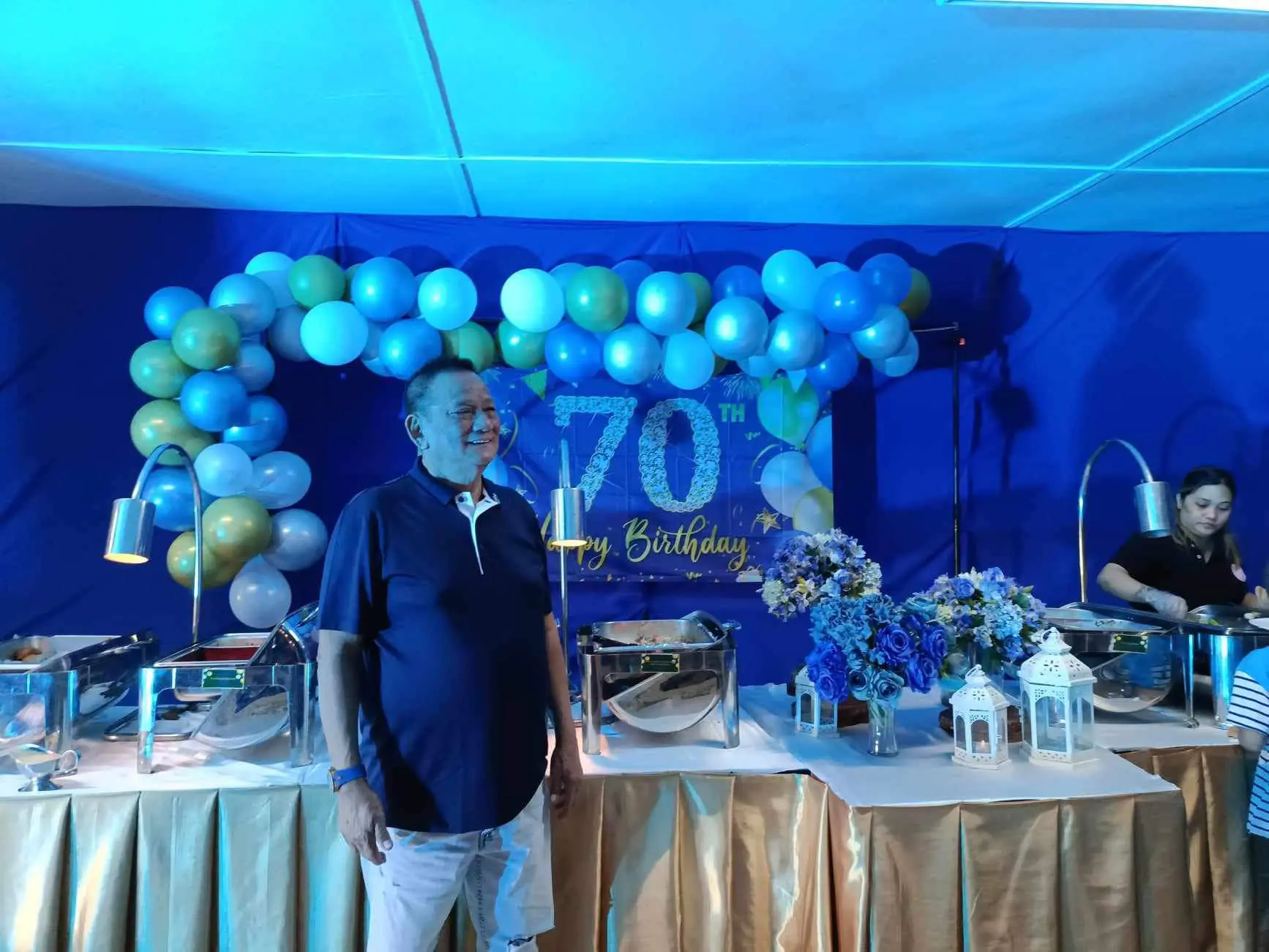 A milestone birthday buffet styled in blue with balloons, flowers, and lanterns.